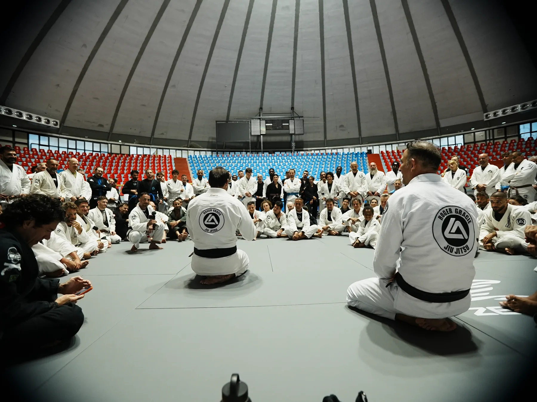 Roger Gracie seated with a large circle of students on the mat